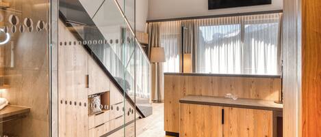 A modern interior with a wooden reception desk, a glass partition, and a staircase.