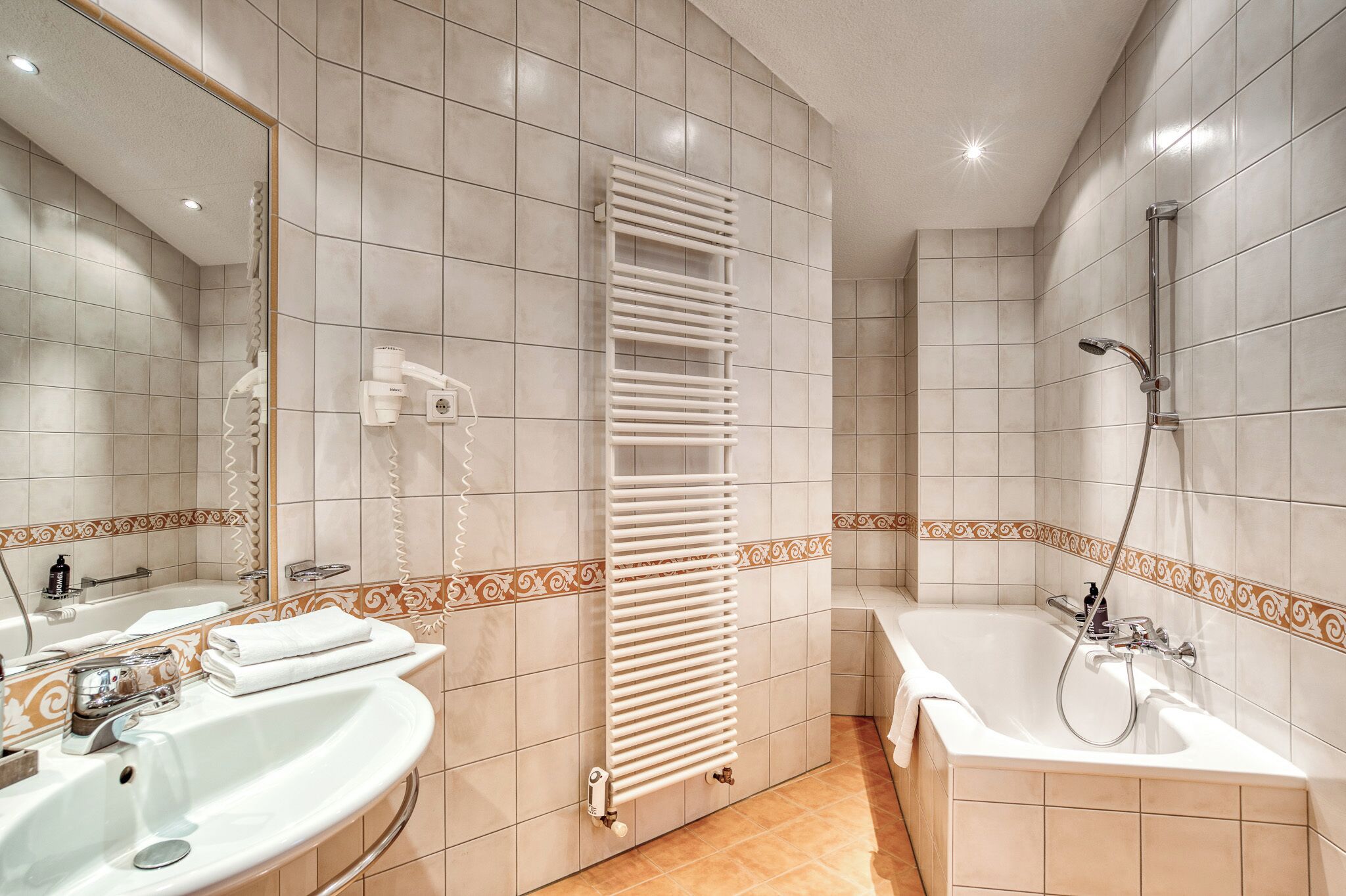 A bathroom with a bathtub, a sink, a mirror, and a towel rack.