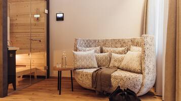 A cozy room with a patterned sofa, a small table with a bottle, and a bench.