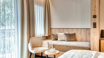 A modern bedroom with a bed, a sofa, a chair, and a small table.