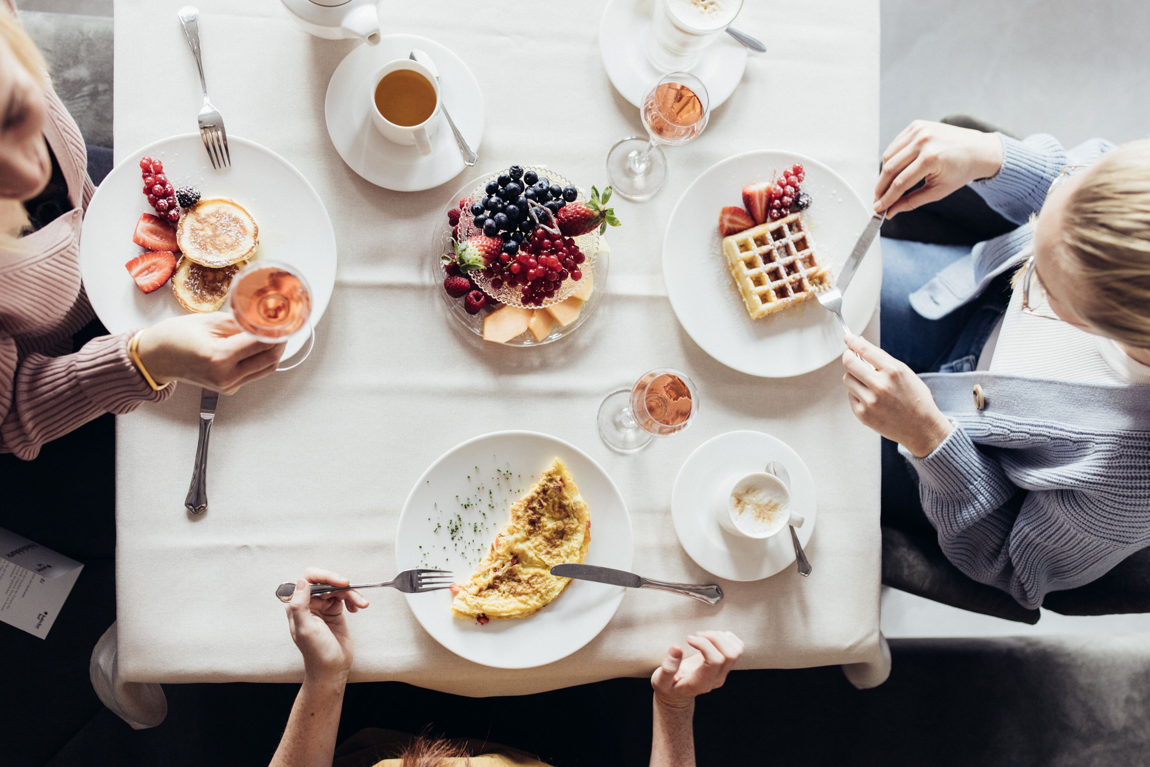 A dining table with various breakfast items including pancakes, waffles, and fruit.