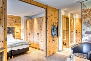A modern hotel room with a bed, wooden wardrobe, a bathroom with a shower, and a dining area with a table and chairs. - Hotel Habicher Hof (Oetz)