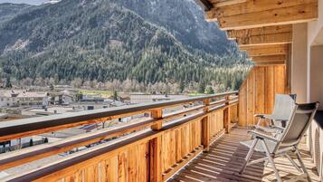 A wooden balcony with a view of a mountainous landscape.