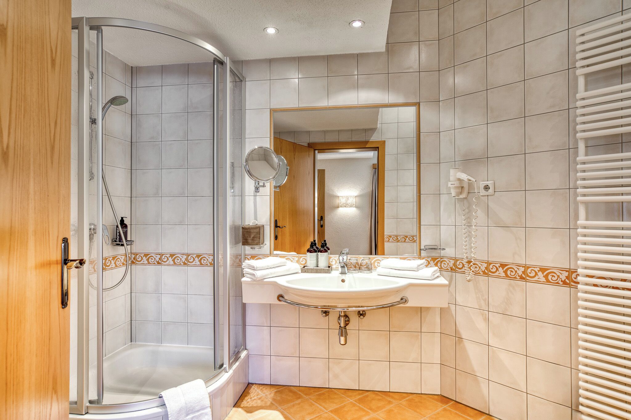 Een moderne badkamer met een douche, wastafel en spiegel.