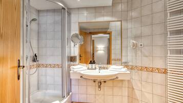 Een moderne badkamer met een douche, wastafel en spiegel.