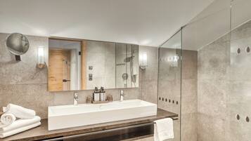 Un baño moderno con un espejo grande, un lavabo blanco y una cabina de ducha con paredes de vidrio.