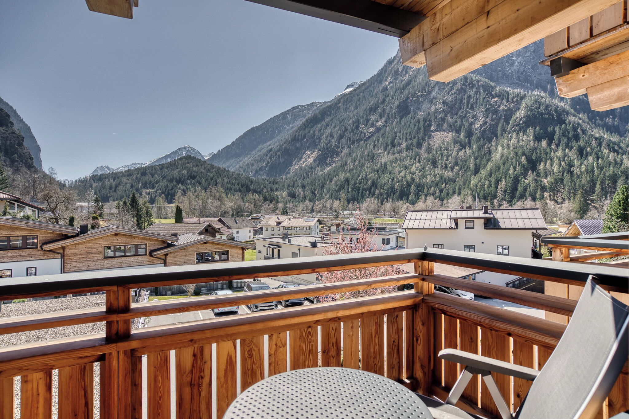 Un balcon en bois offrant une vue sur un village de montagne et sur les maisons.