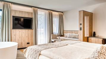 Ein modernes Hotelzimmer mit einem großen Bett, einem an der Wand befestigten Fernseher, einem Schreibtisch und einem Stuhl.
