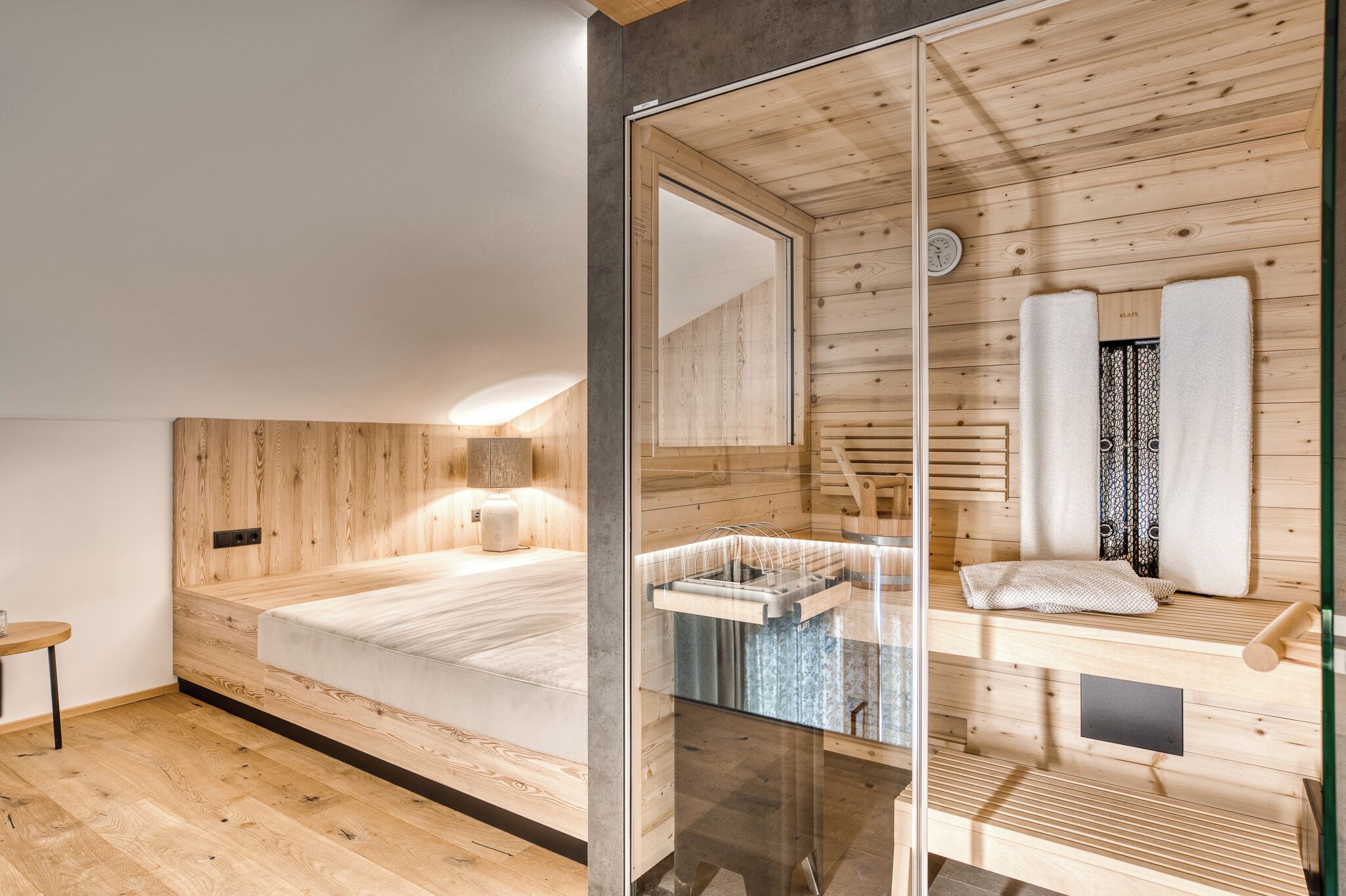Un dormitorio moderno con pared de listones de madera, cabina de ducha de vidrio y suelo de madera.