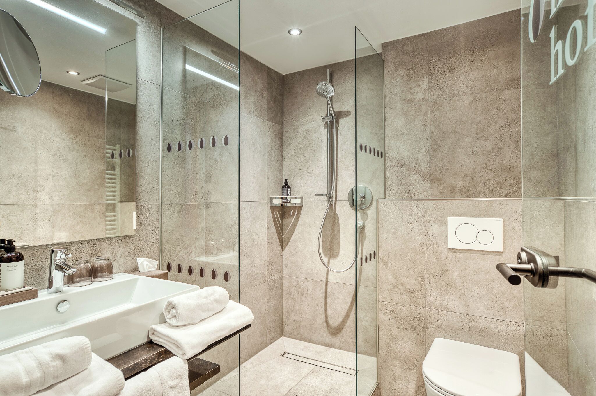 Une salle de bain moderne avec une douche à parois de verre, une baignoire blanche et des toilettes.