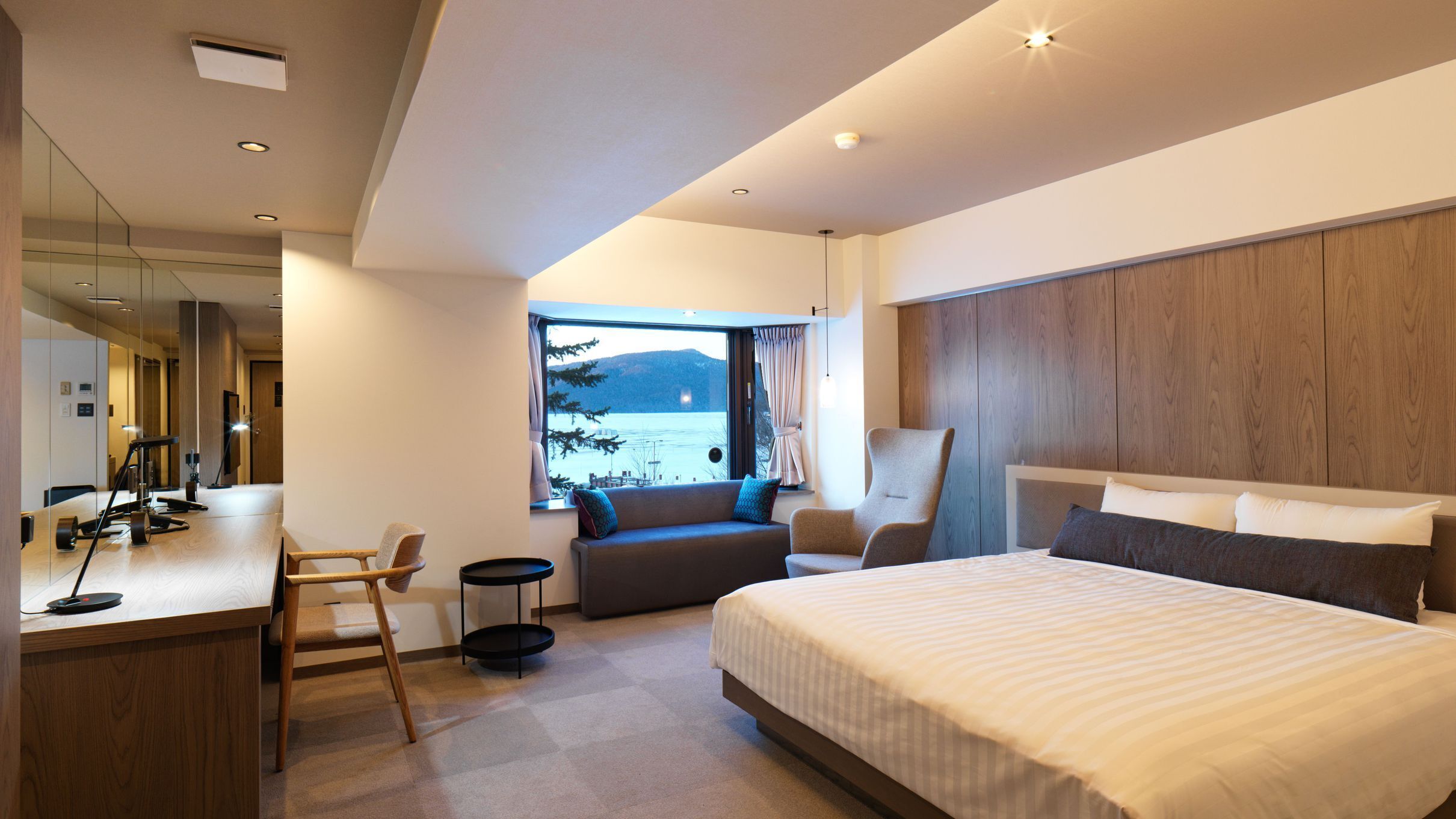 Ein modernes Hotelzimmer mit einem großen Bett, einem Schreibtisch, einem Sessel und einer Couch.