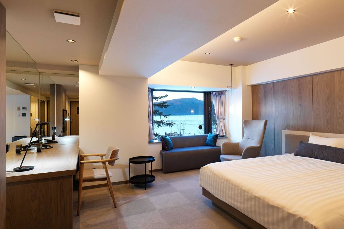 Une chambre d’hôtel moderne avec un grand lit, un bureau, une chaise et un canapé.
