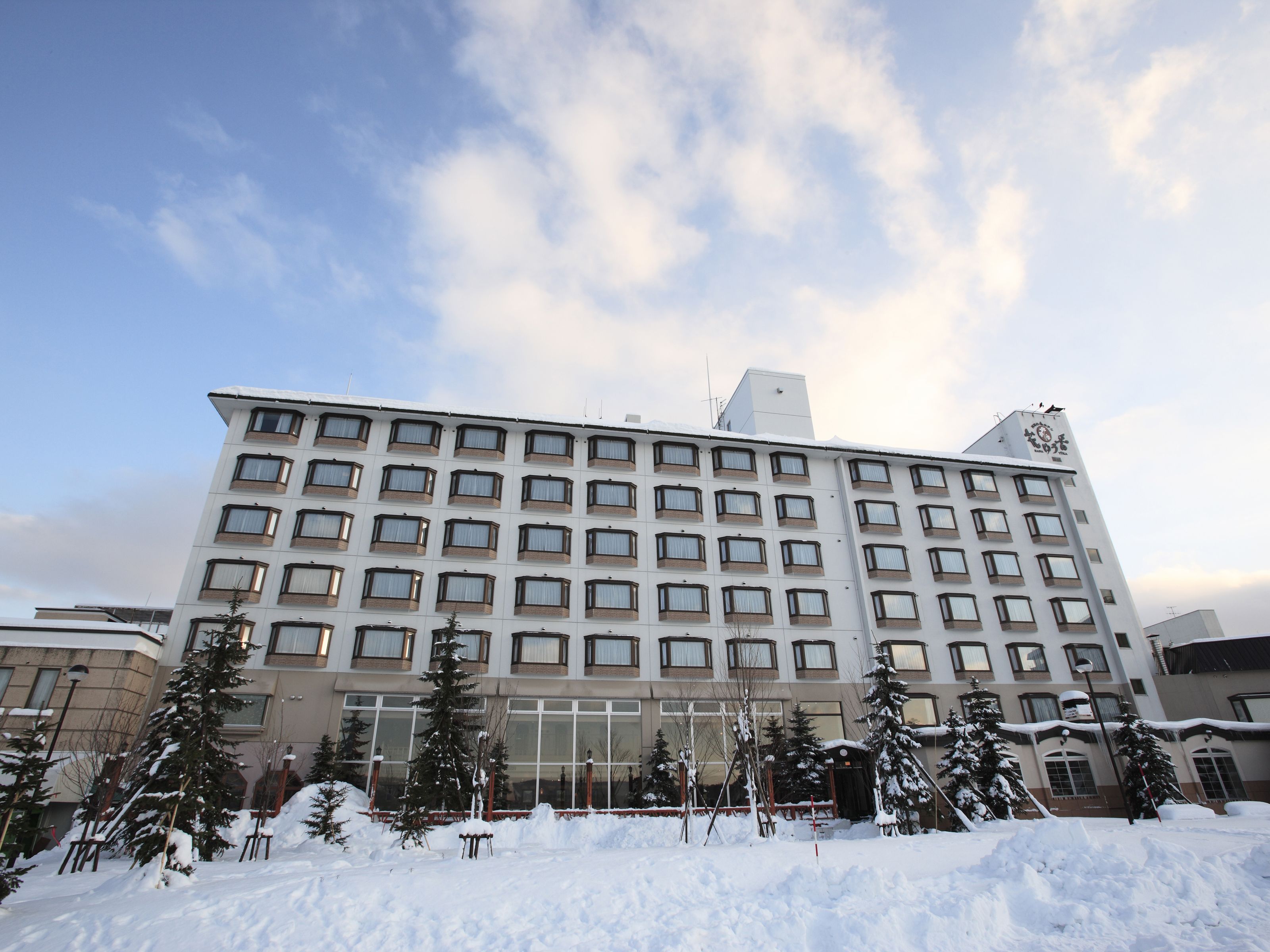 A multi-story hotel with a symmetrical facade, large windows, and a snow-covered ground.