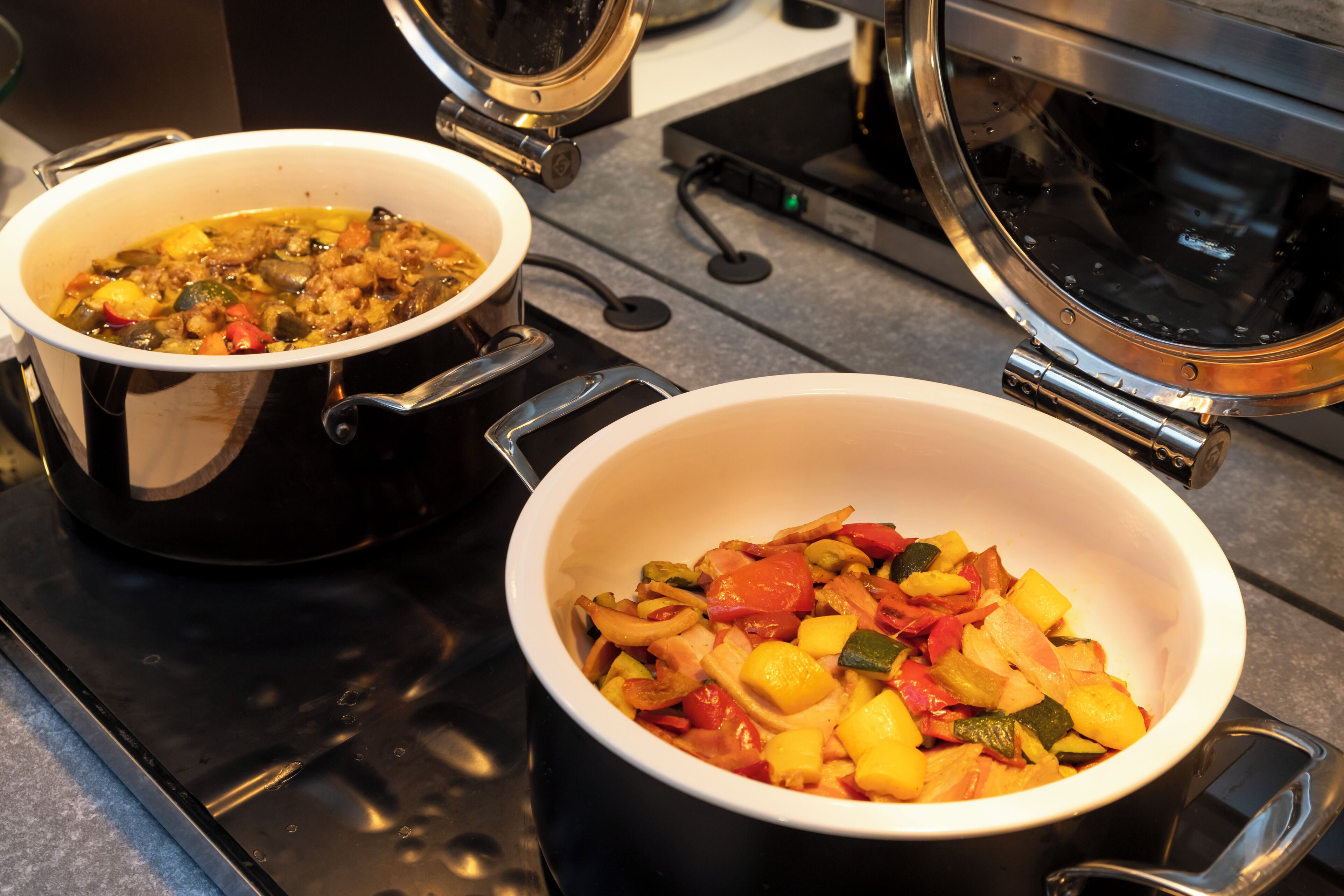 Two pots on a stove with food inside.