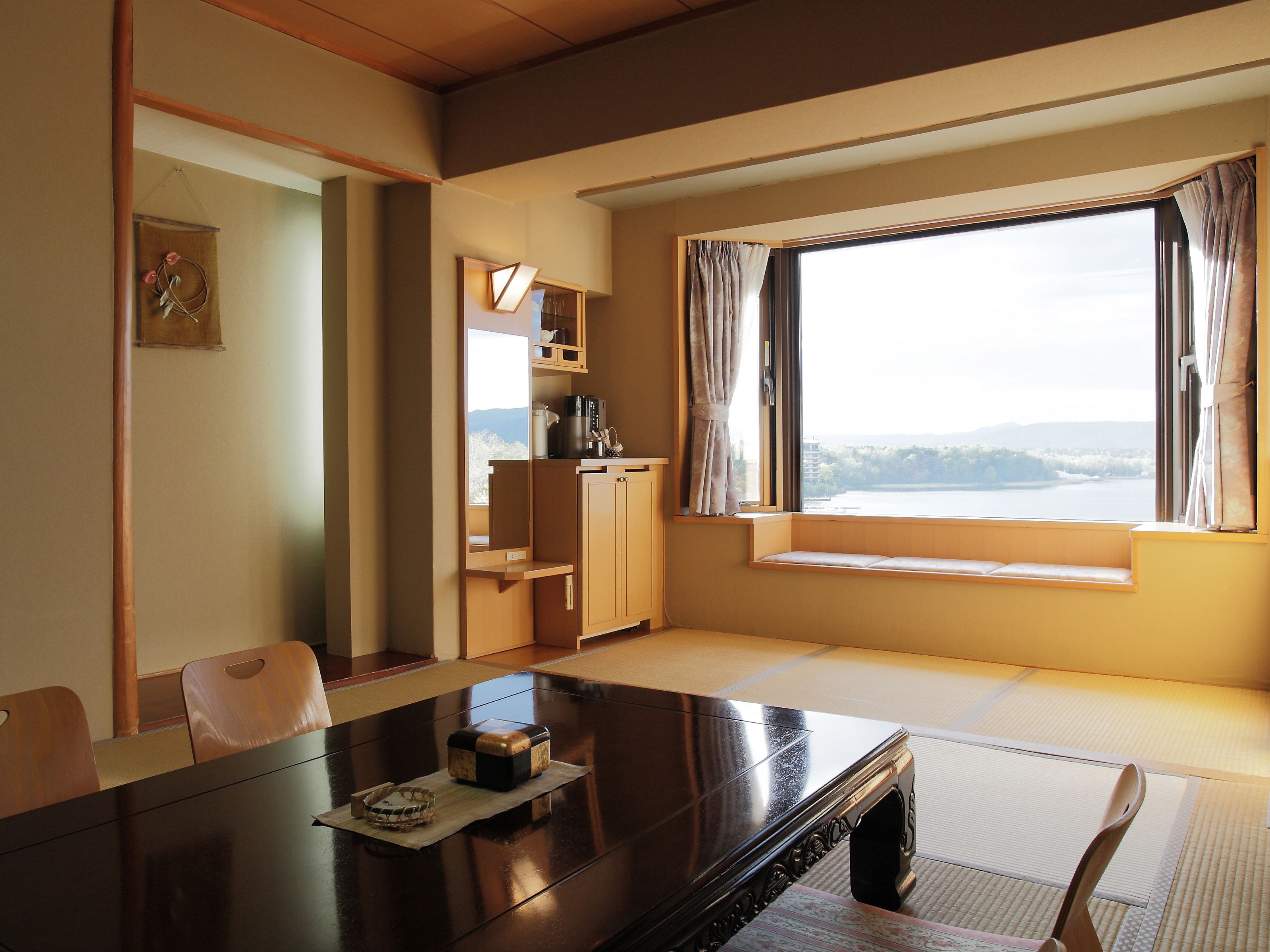 Una habitación con una mesa de comedor, sillas, un armario pequeño y una ventana con vistas.