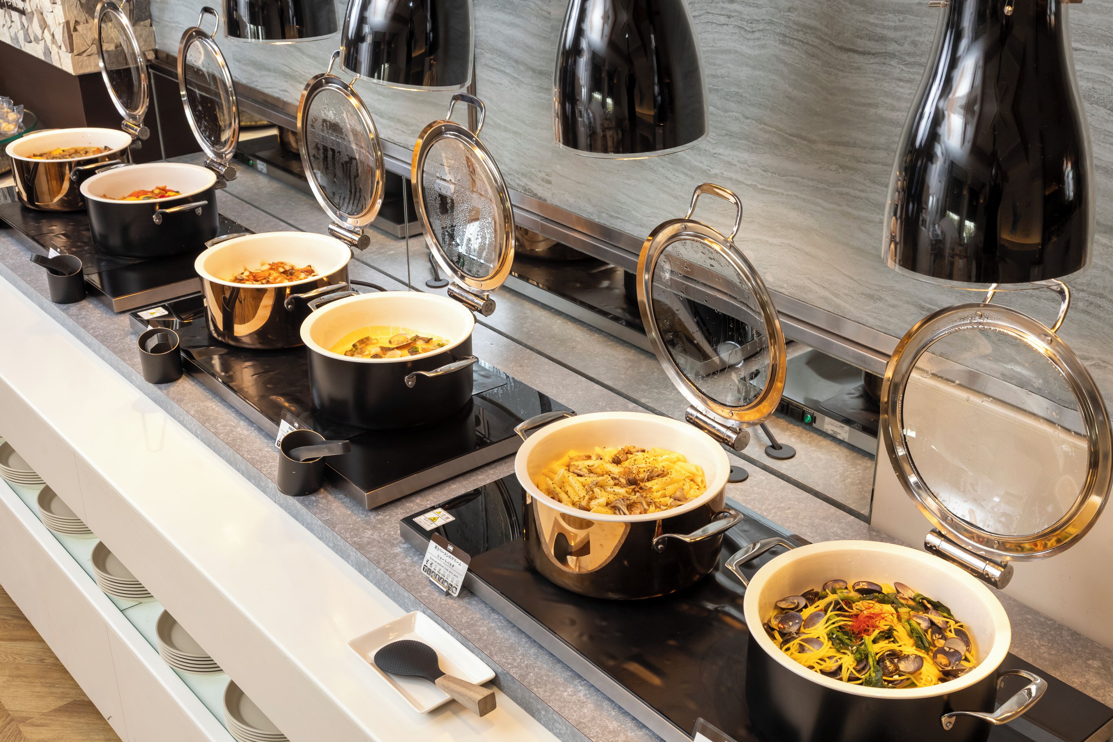 Un buffet composé de plusieurs présentoirs en libre-service, chacun contenant un plat et un couvercle.