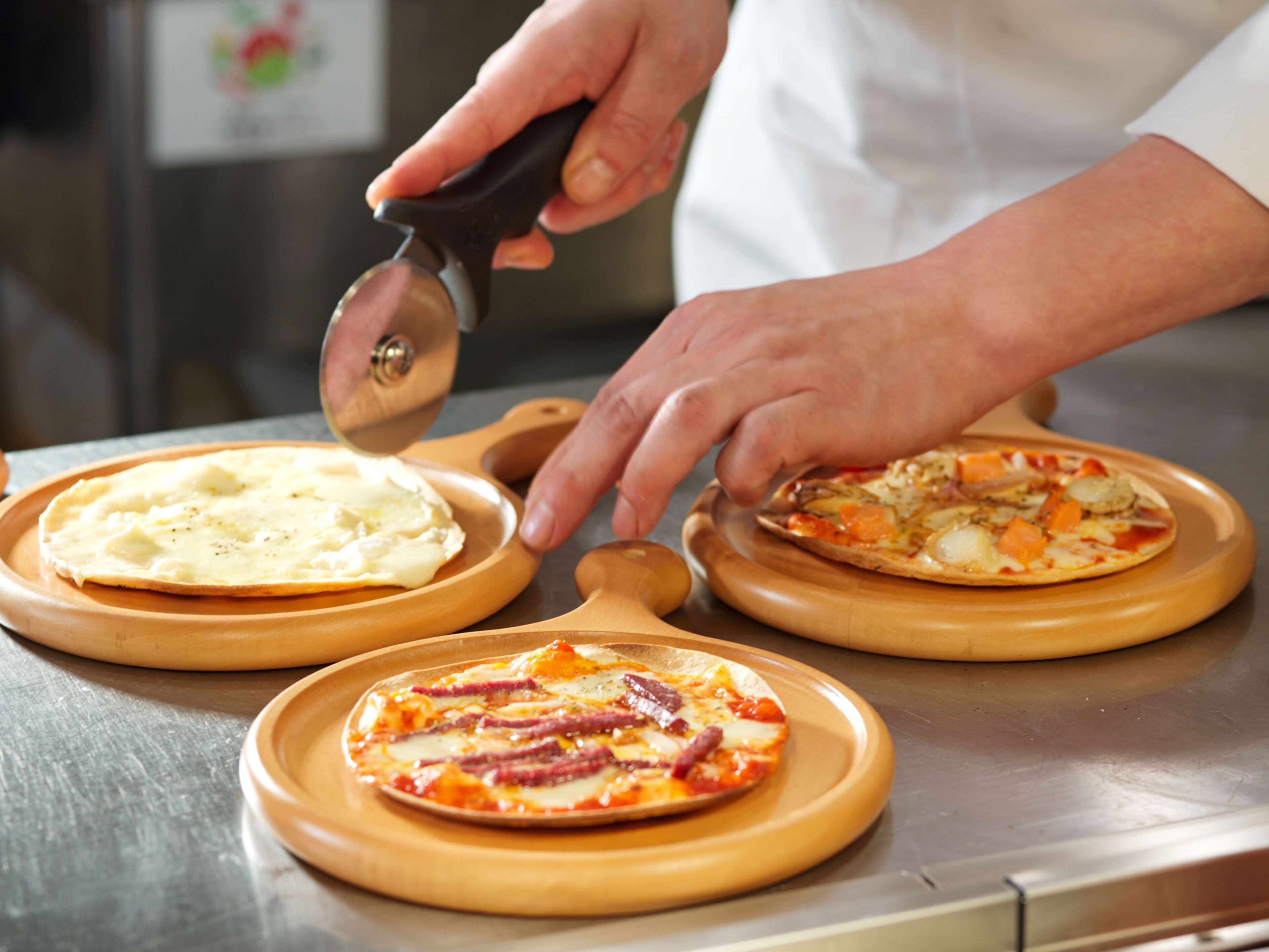 A chef preparing pizzas on wooden boards.