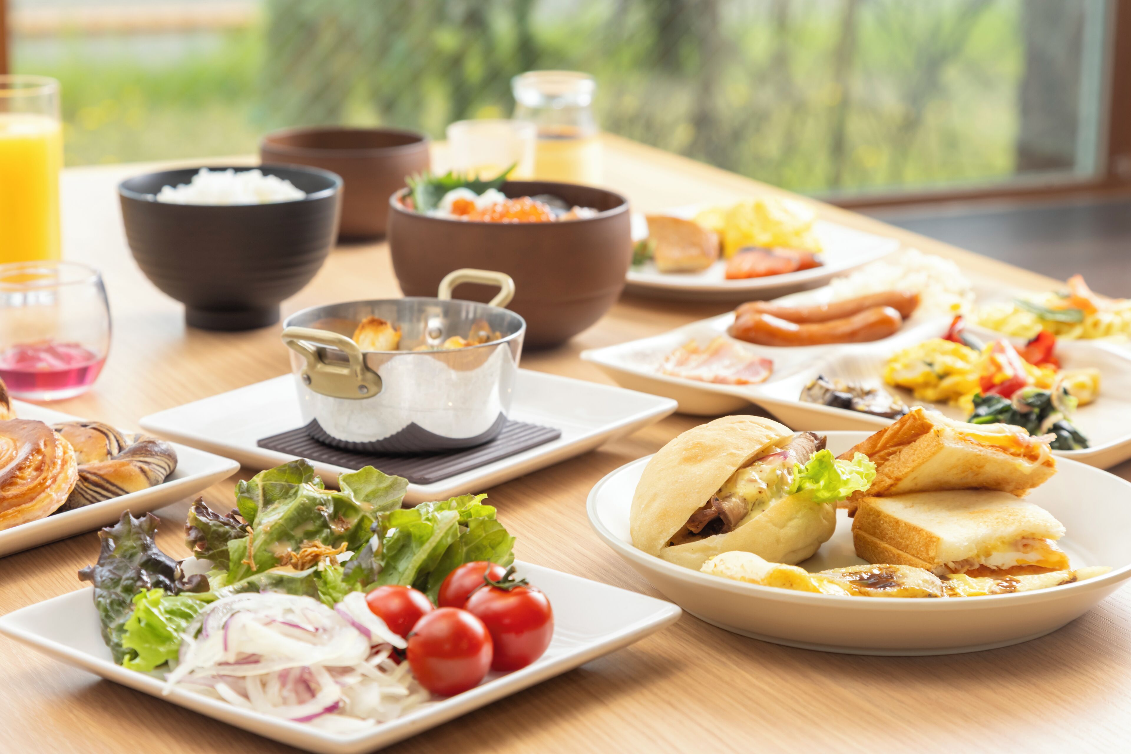 A table with various dishes including a salad, sandwiches, and bowls of food.