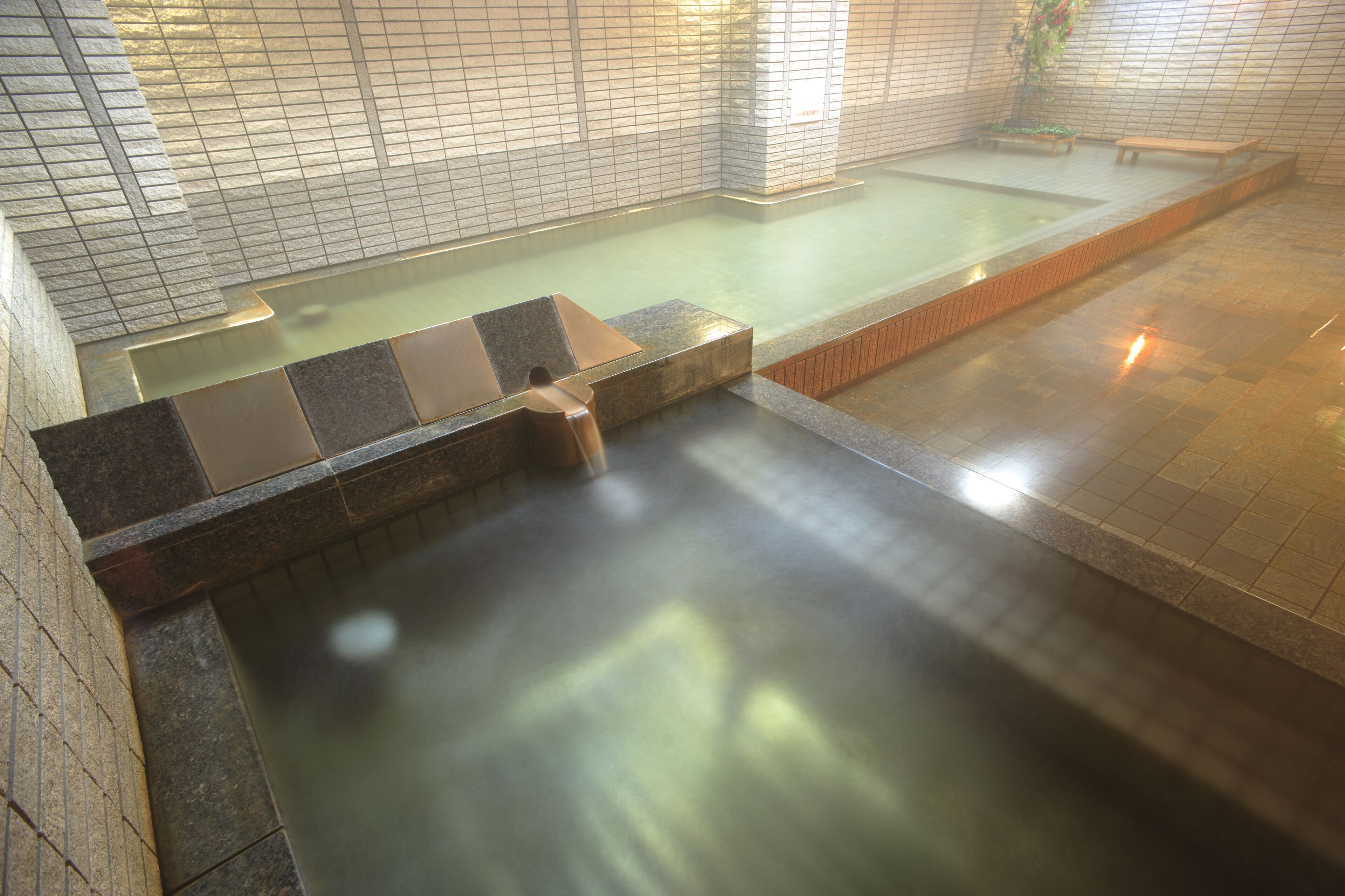 Un área de spa con un jacuzzi, paredes con azulejos y una banca.