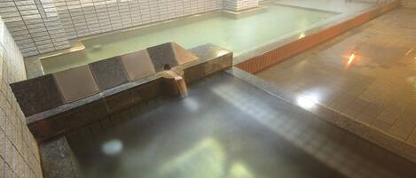 Un área de spa con un jacuzzi, paredes con azulejos y una banca.
