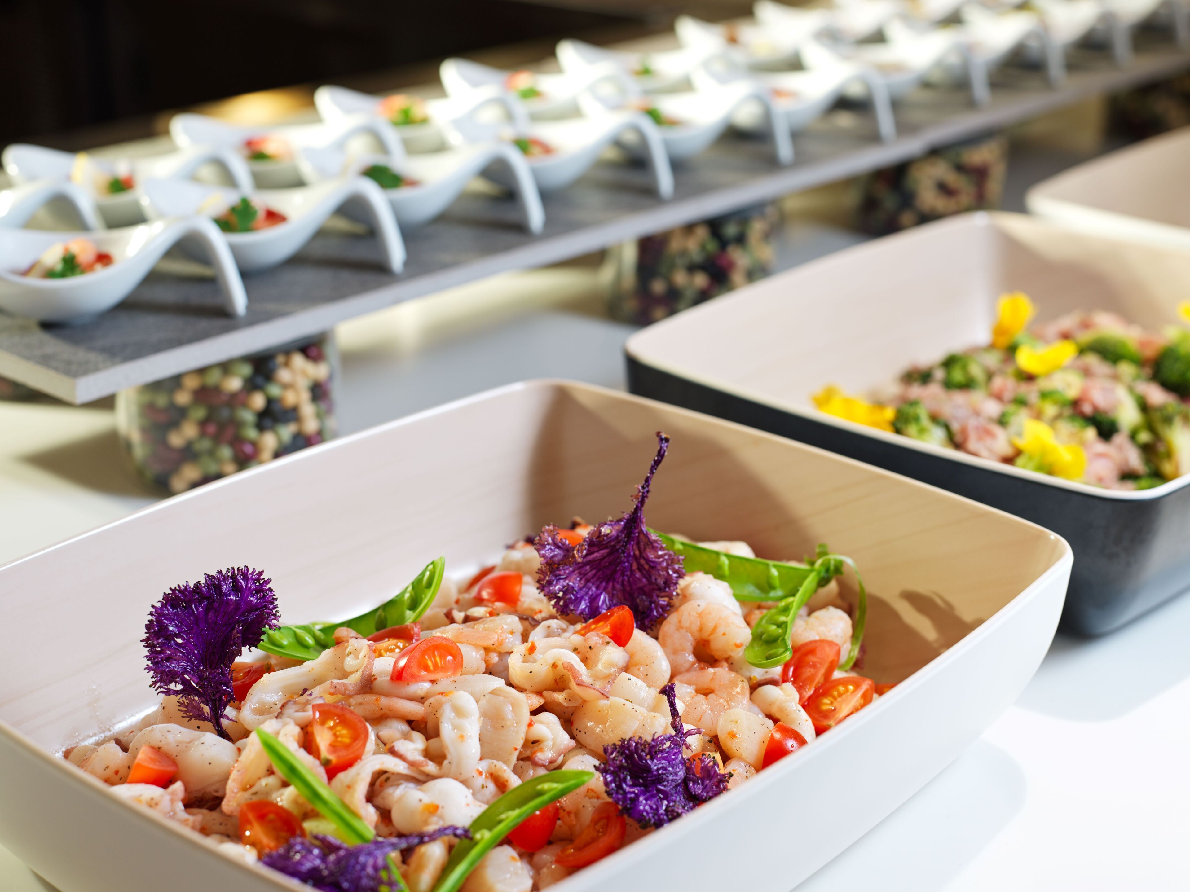 Un bufé con diversos platos, entre ellos mariscos y ensaladas, dispuesto en una mesa.