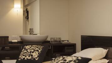 A modern bedroom with a large bed, a bedside table with a white basin, and a mirror above the sink.