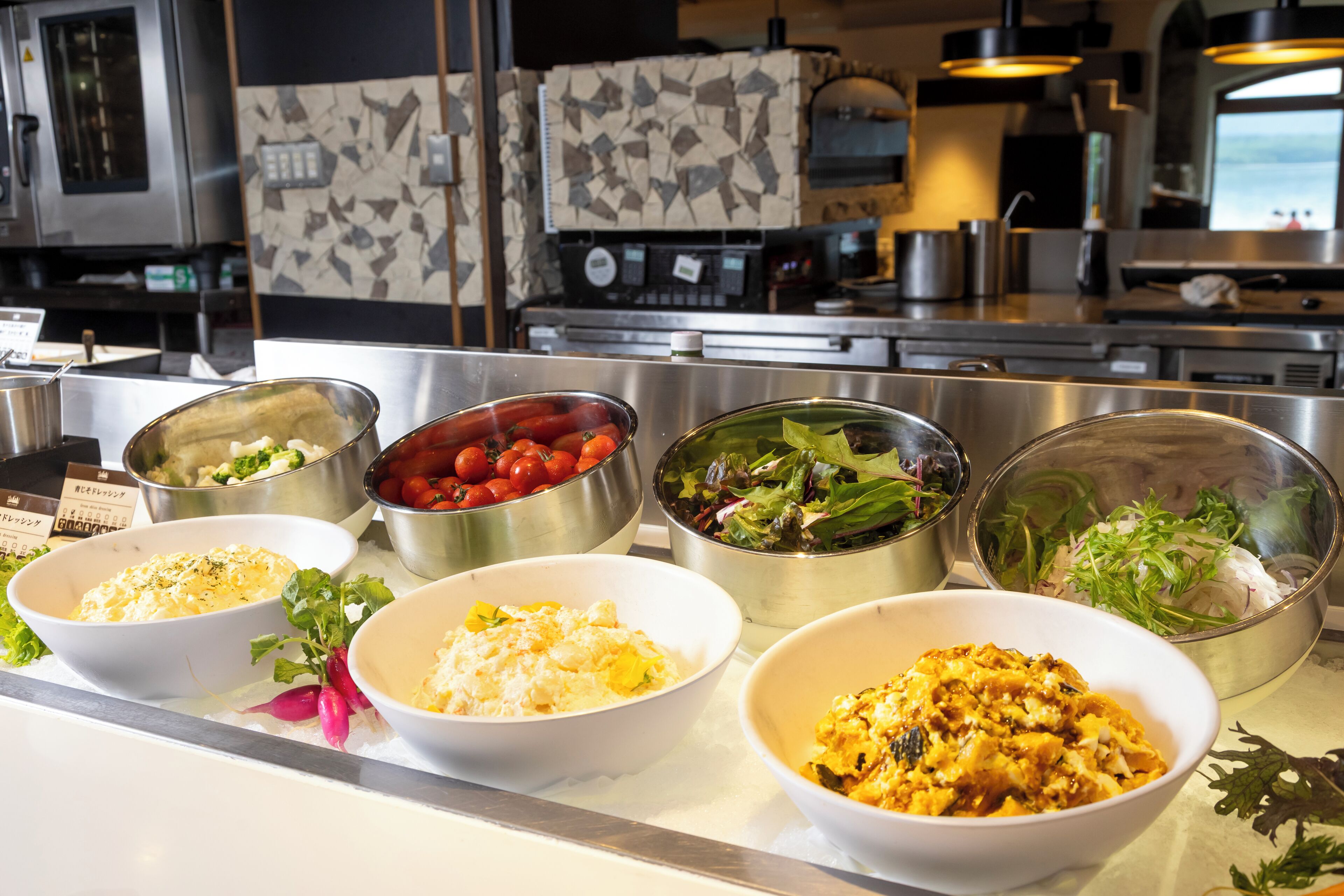 A buffet with various dishes including salads, vegetables, and rice.