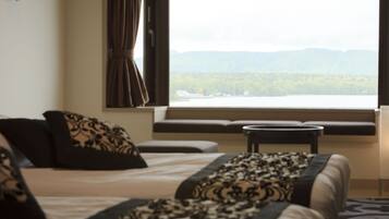 Une chambre d’hôtel avec deux lits, une fenêtre donnant sur les montagnes et une petite table.