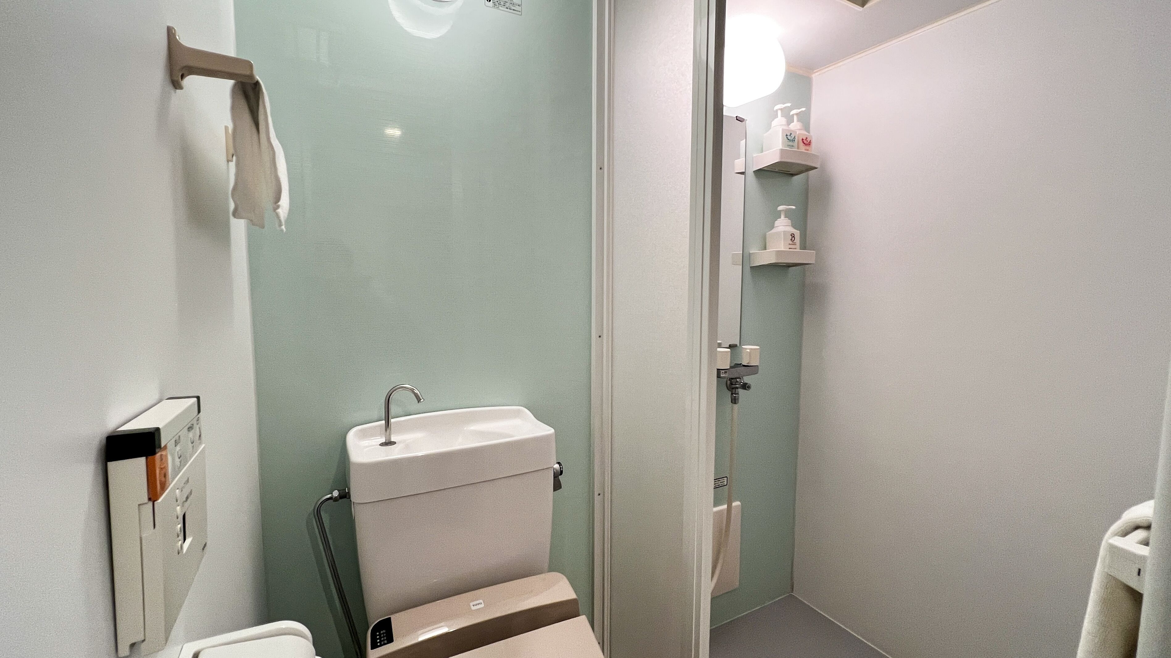 A small bathroom with a toilet, sink, and shower.