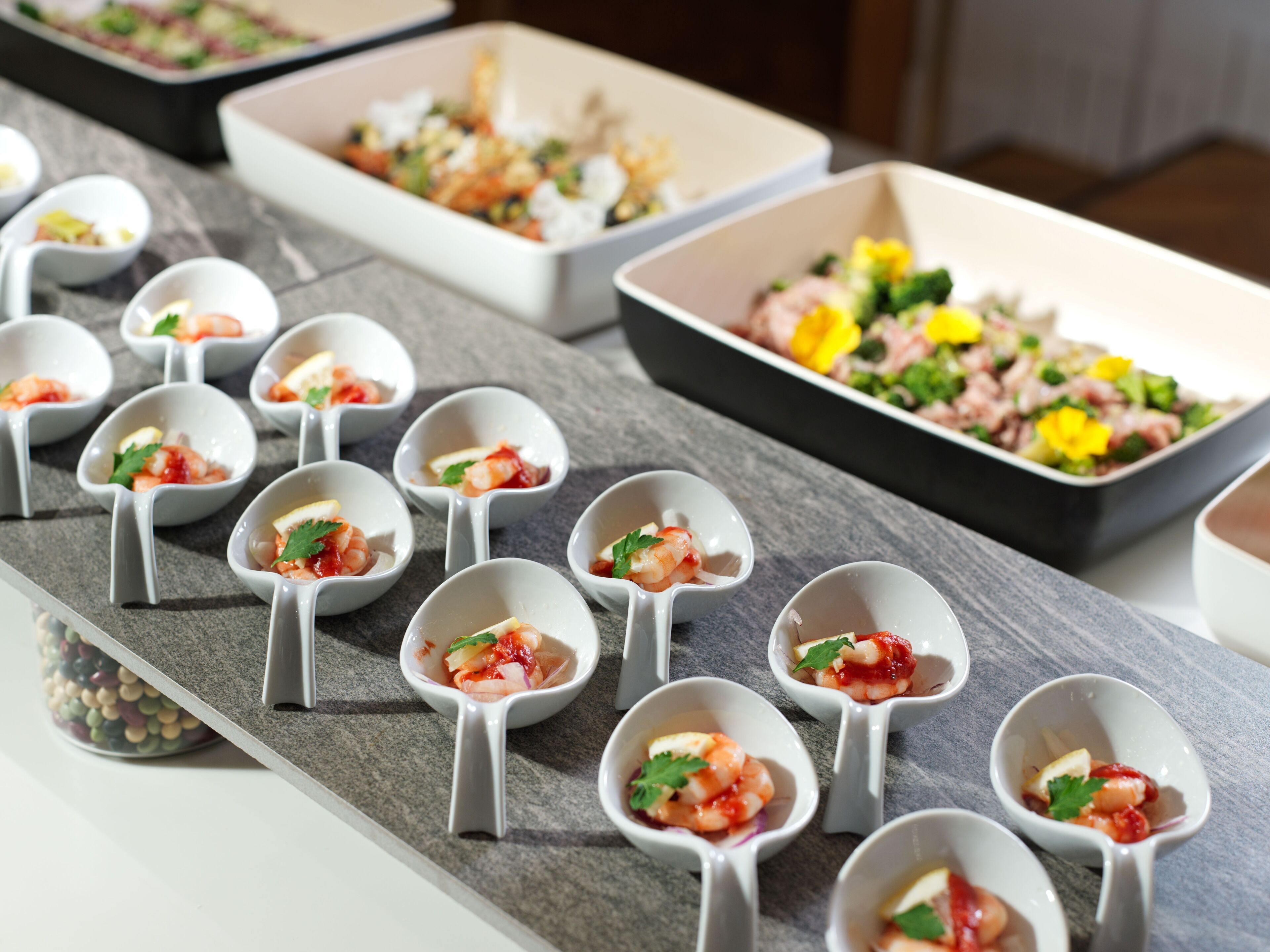 A buffet table with various dishes in small bowls and rectangular trays.