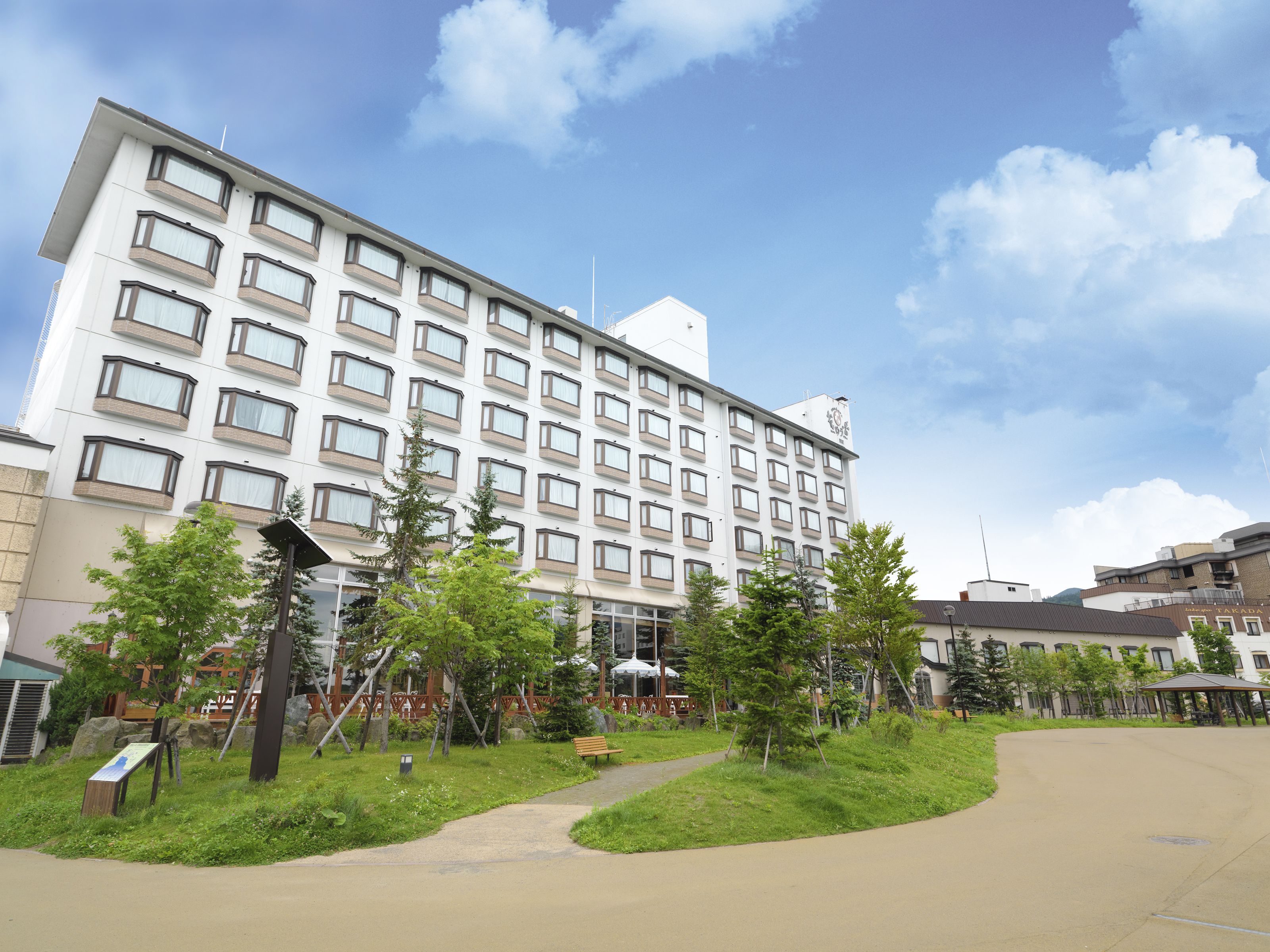 A multi-story hotel with a modern design, featuring a central courtyard with trees and a pathway.