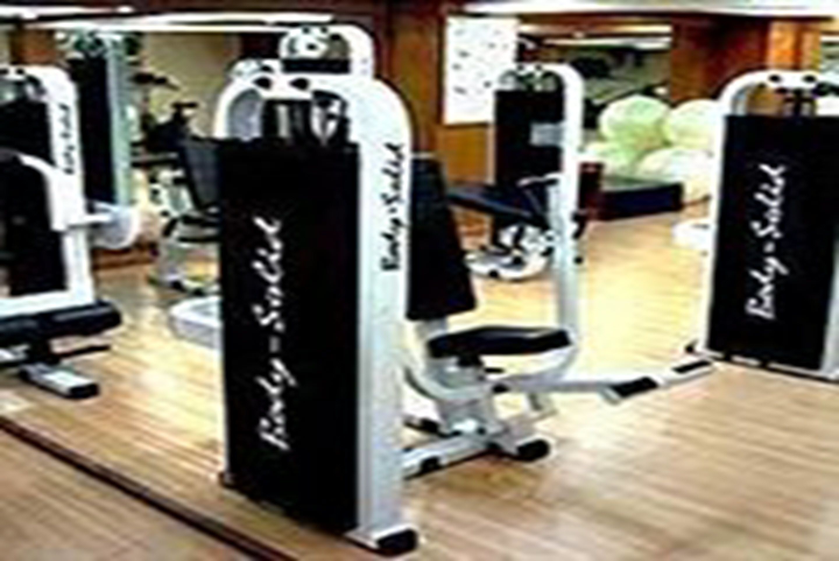 Une salle de sport équipée de matériel d’exercice, notamment une machine à presse pour les jambes et une machine à presse pour les pectoraux.