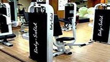Une salle de sport équipée de matériel d’exercice, notamment une machine à presse pour les jambes et une machine à presse pour les pectoraux.