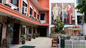 A hotel with a reception area, potted plants, and a sign for the PJ Watergate Hotel. - PJ Watergate Hotel (Bangkok)