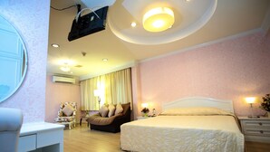 A hotel room with a large bed, a sofa, a desk, and a ceiling projector. - PJ Watergate Hotel (Bangkok)