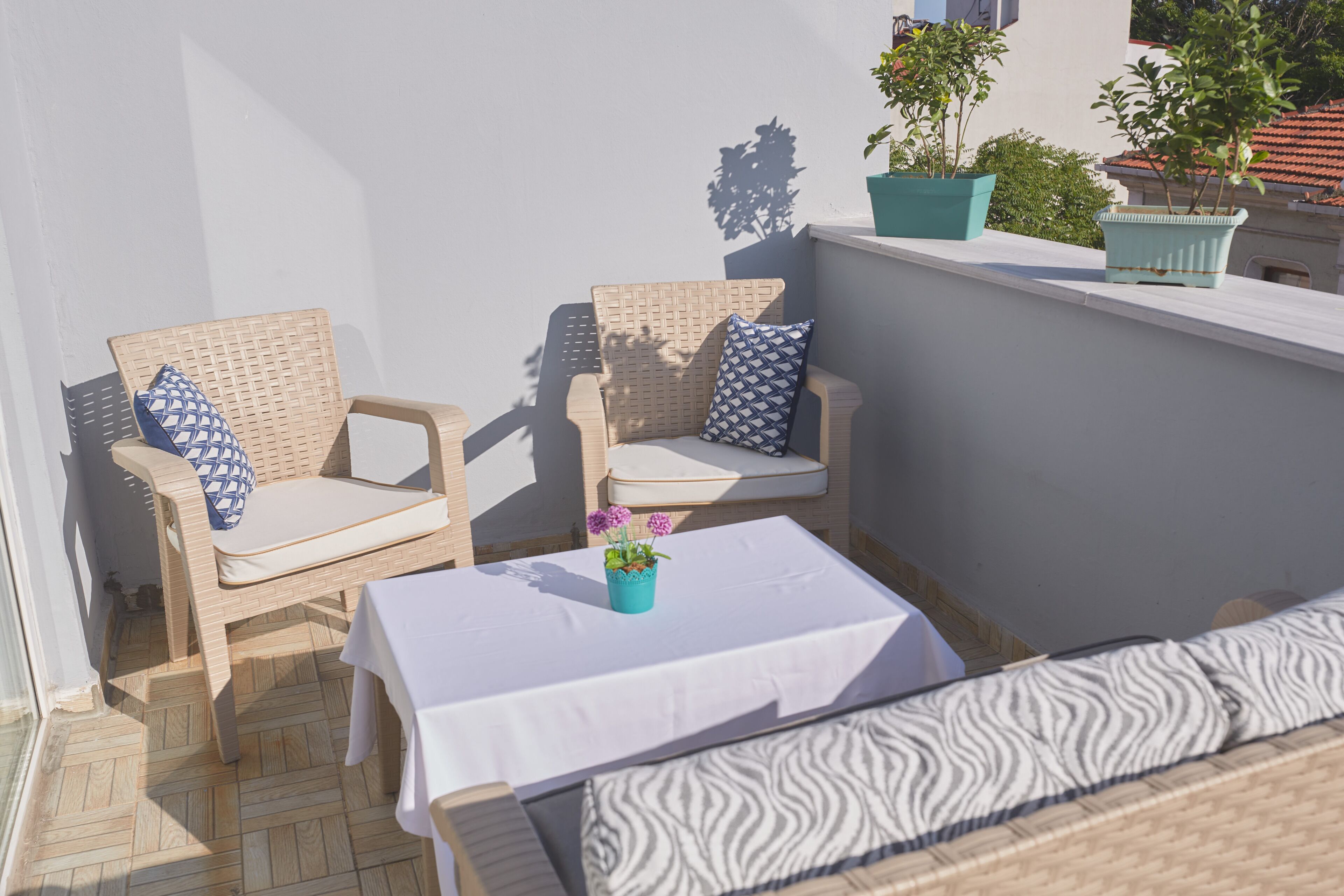 A balcony with wicker furniture, a small table, and potted plants.
