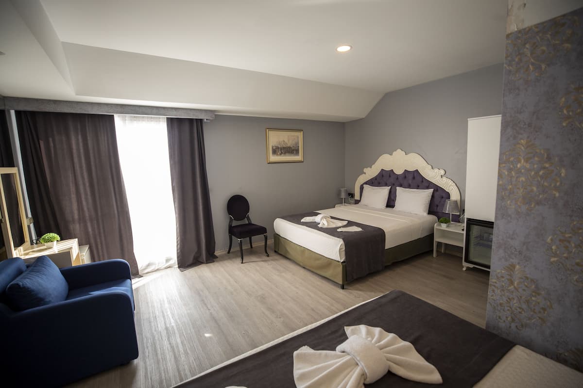 Ein modernes Hotelzimmer mit einem großen Bett, einem blauen Sofa, einem Sessel und einem Schreibtisch.
