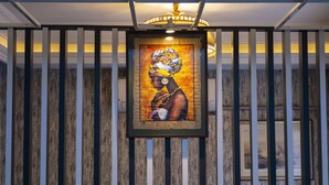 A framed artwork of a woman in traditional attire hanging on a wooden wall with vertical slats. - Albatros Hagia Sophia - Special Class (Istanbul)