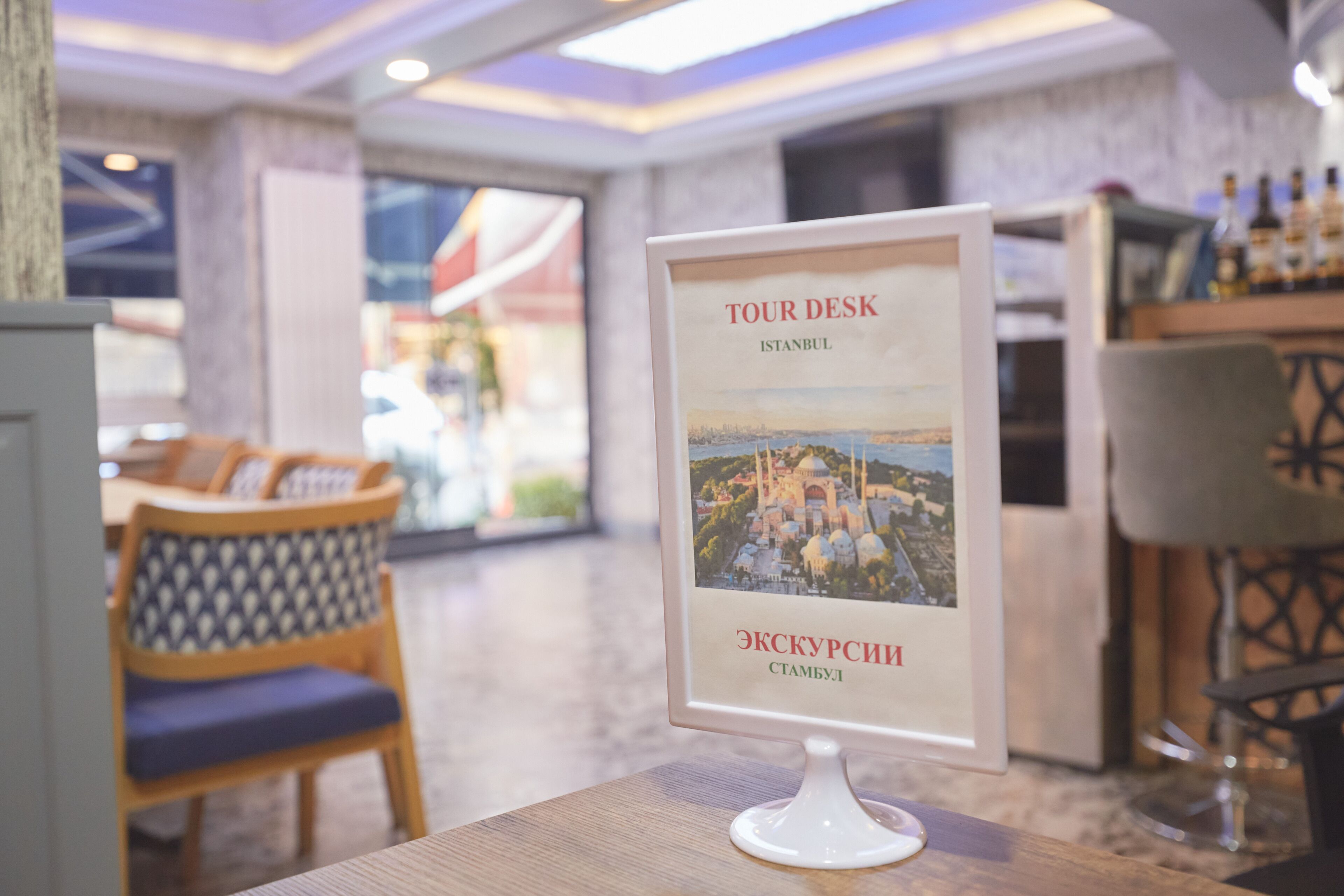 A tour desk with a sign indicating it's in Istanbul, featuring a view of a historic building.