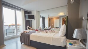 A hotel room with a large bed, a flat-screen TV, a balcony with a table and chairs, and a view of the city. - Albatros Hagia Sophia - Special Class (Istanbul)