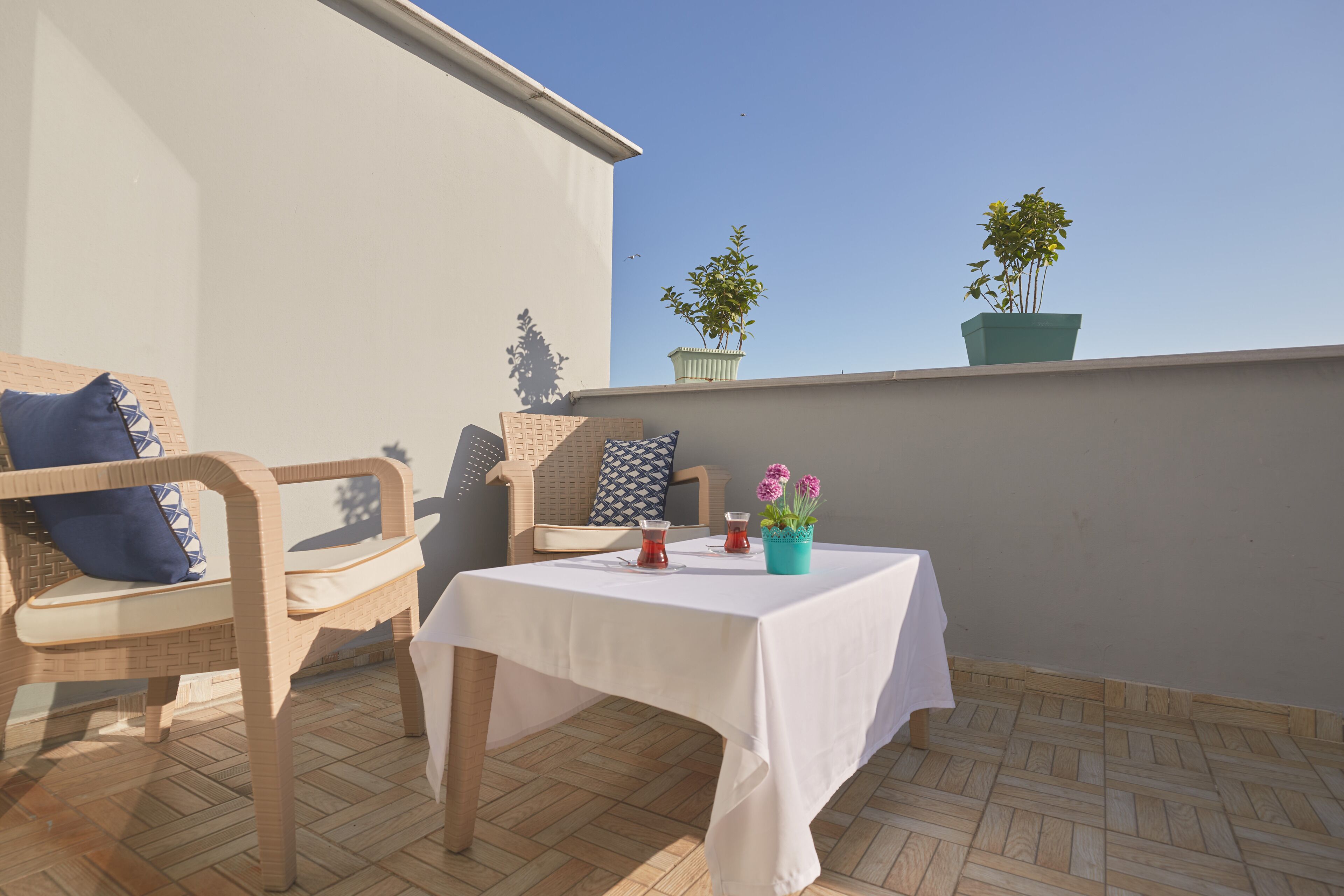 A balcony with wicker furniture, a table with a white tablecloth, and potted plants.