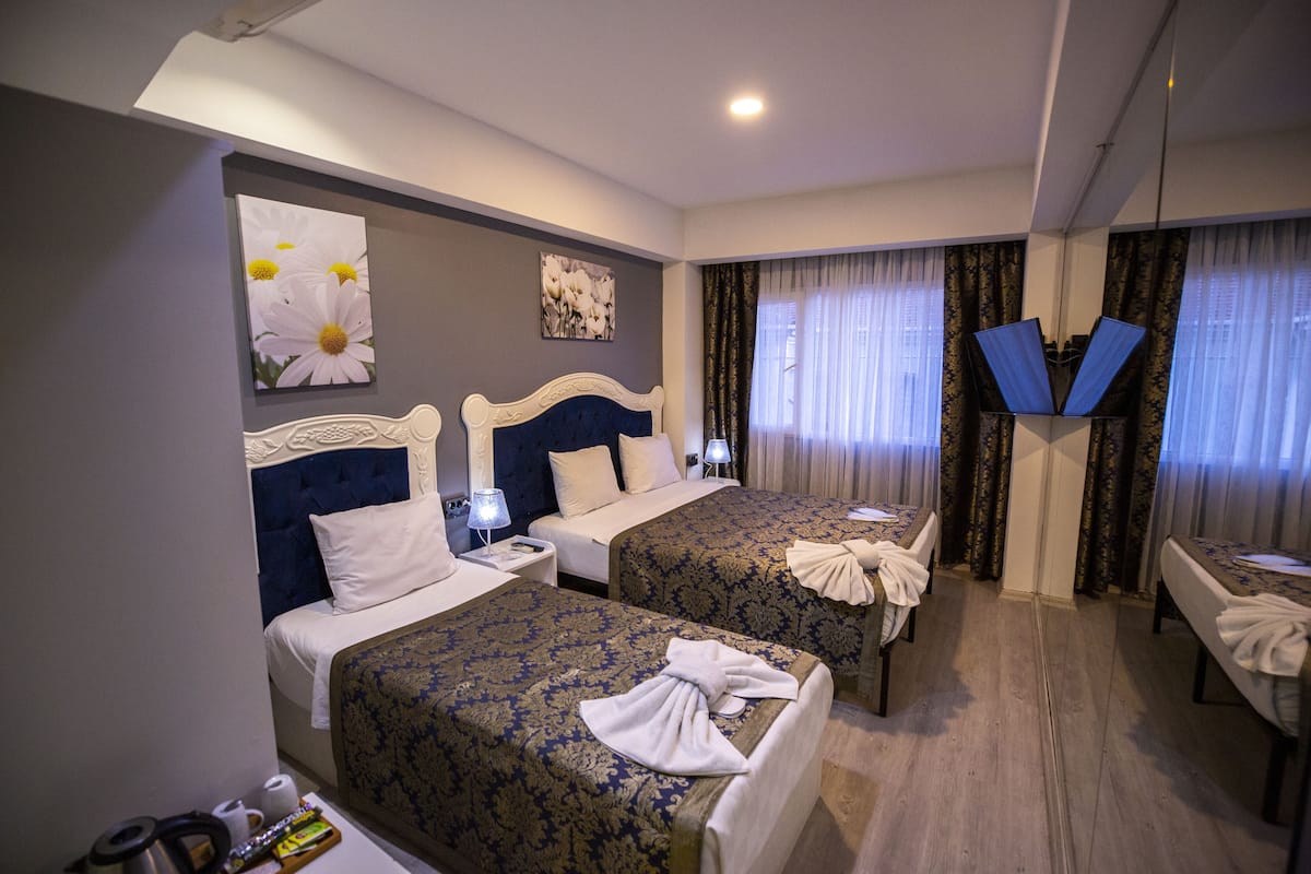Ein Hotelzimmer mit zwei Betten, einem Schreibtisch und einem Spiegel.