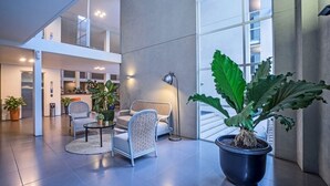 Eine großzügige Lobby mit hoher Decke, modernen Möbeln und großen Fenstern, die für viel Tageslicht sorgen.