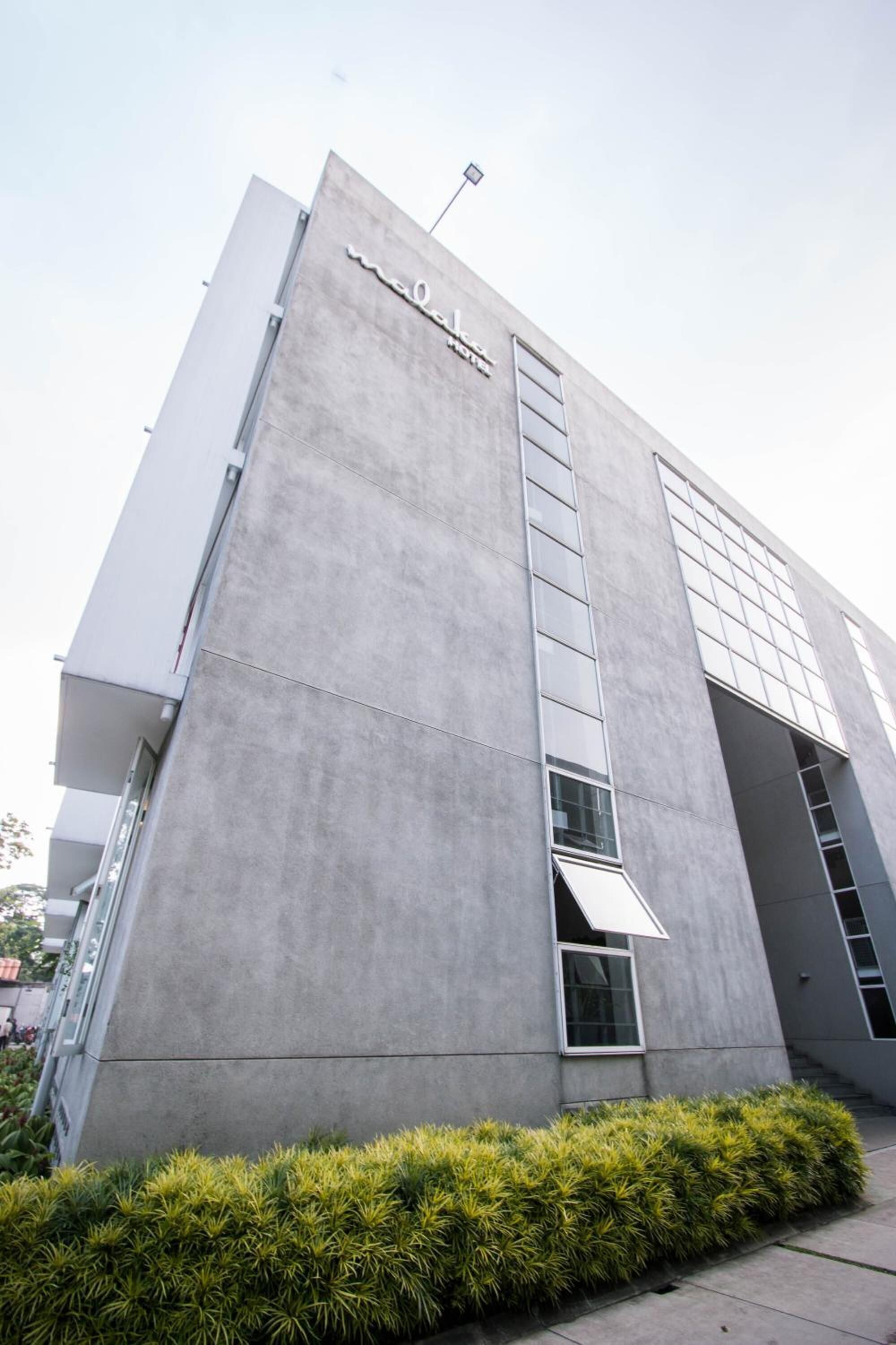 A modern building with a concrete facade, large windows, and a visible entrance.