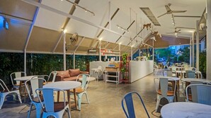 Ein Café mit Tischen, Stühlen, einer Theke und einer Treppe zu einer erhöhten Ebene.