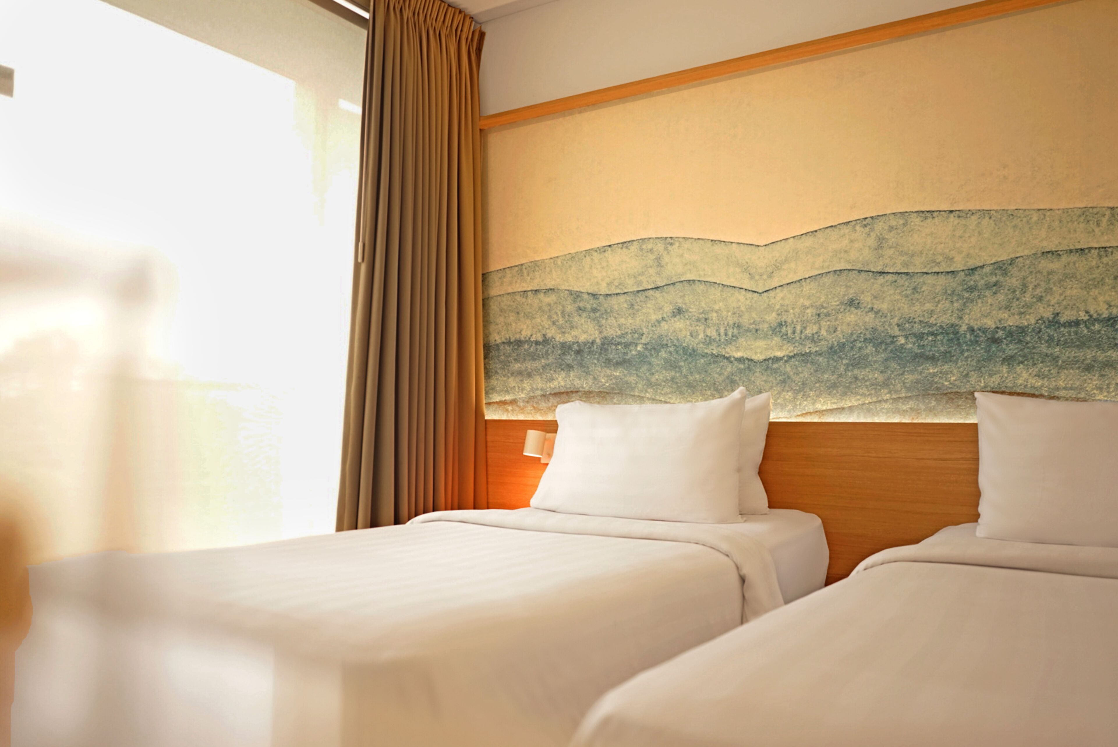 Una camera d'albergo con due letti, un grande quadro astratto appeso al muro e una finestra con tende.