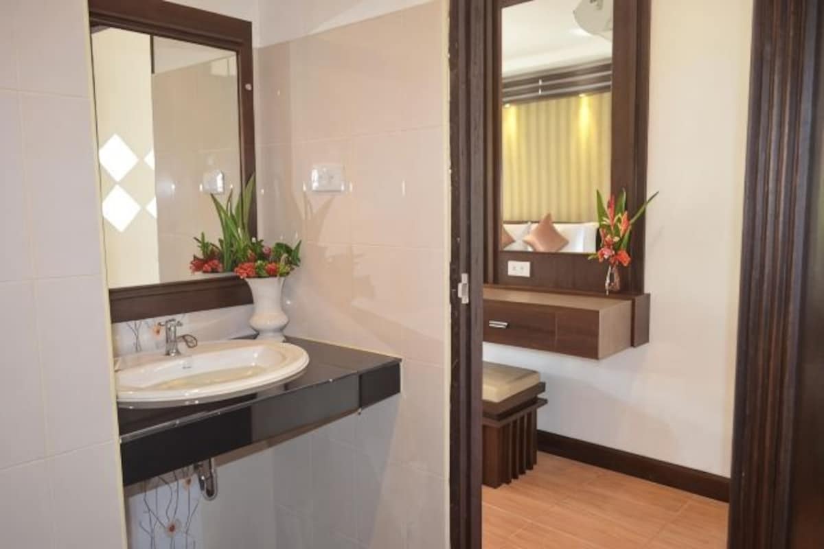 A bathroom with a sink, mirror, and potted plants.