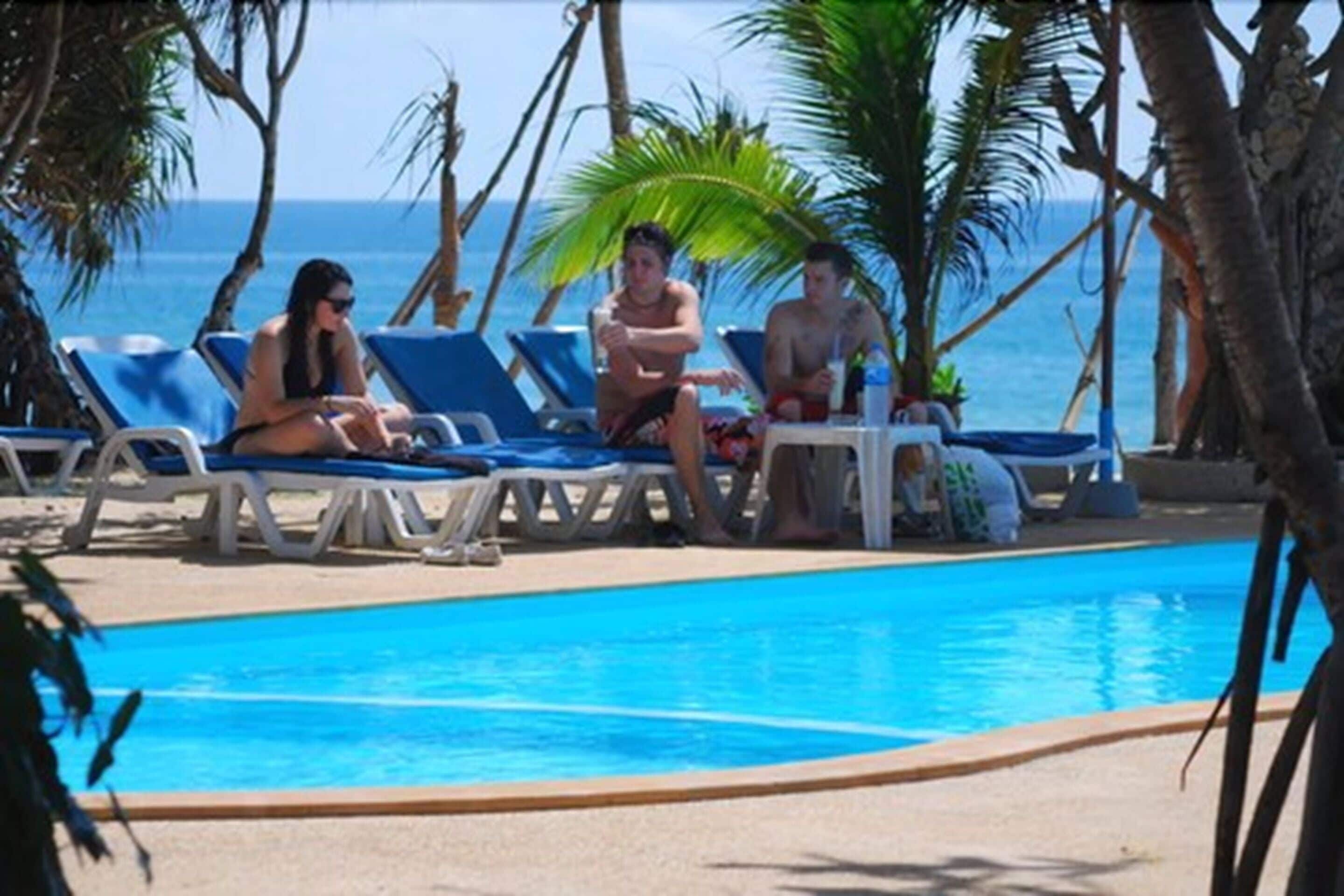 A poolside area with lounge chairs and a clear view of the ocean.
