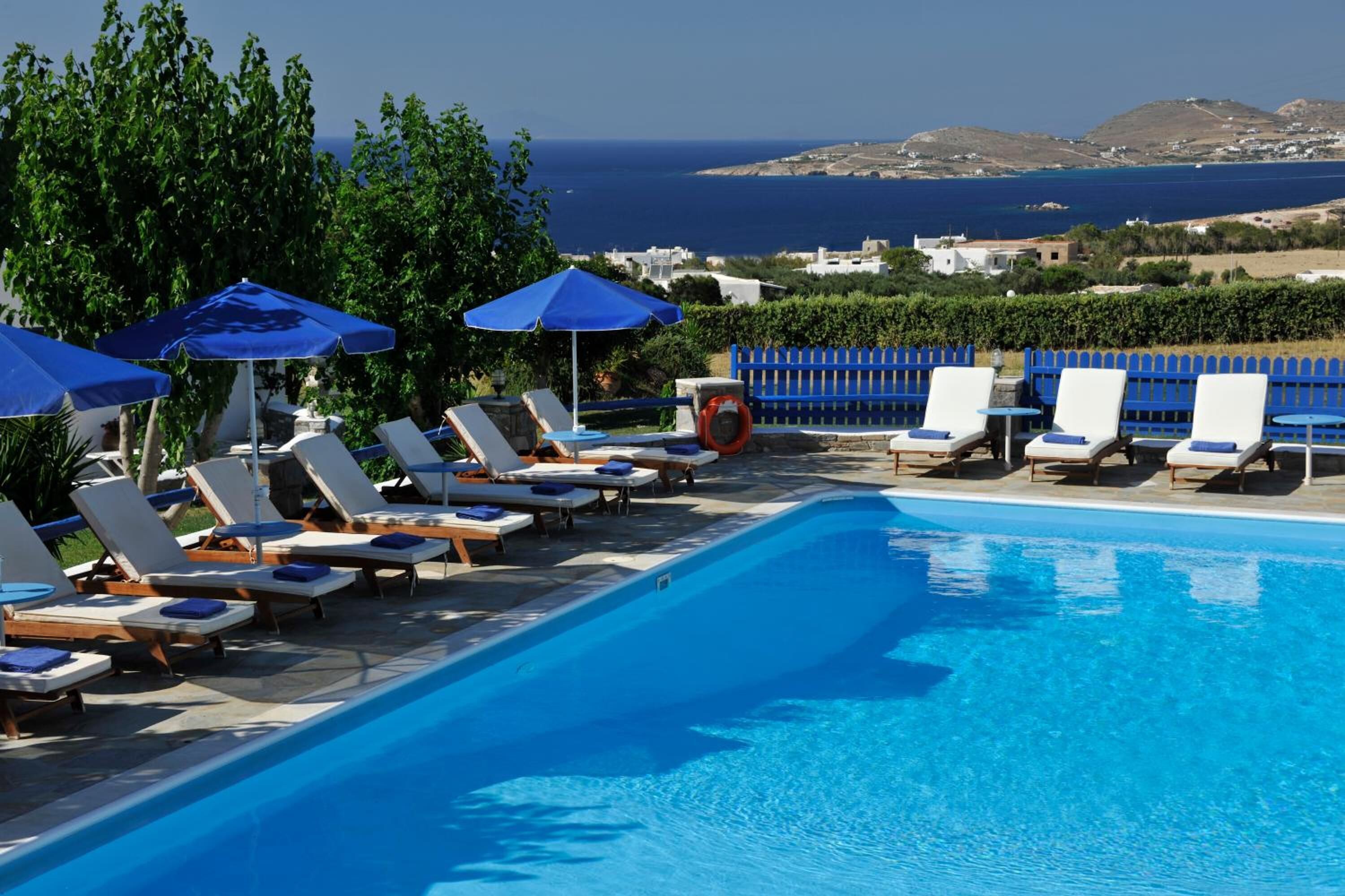 A poolside area with lounge chairs and umbrellas, overlooking a coastal landscape.