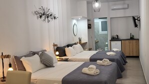 Una habitación de hotel moderna con dos camas, un escritorio, un espejo y una kitchenette pequeña.